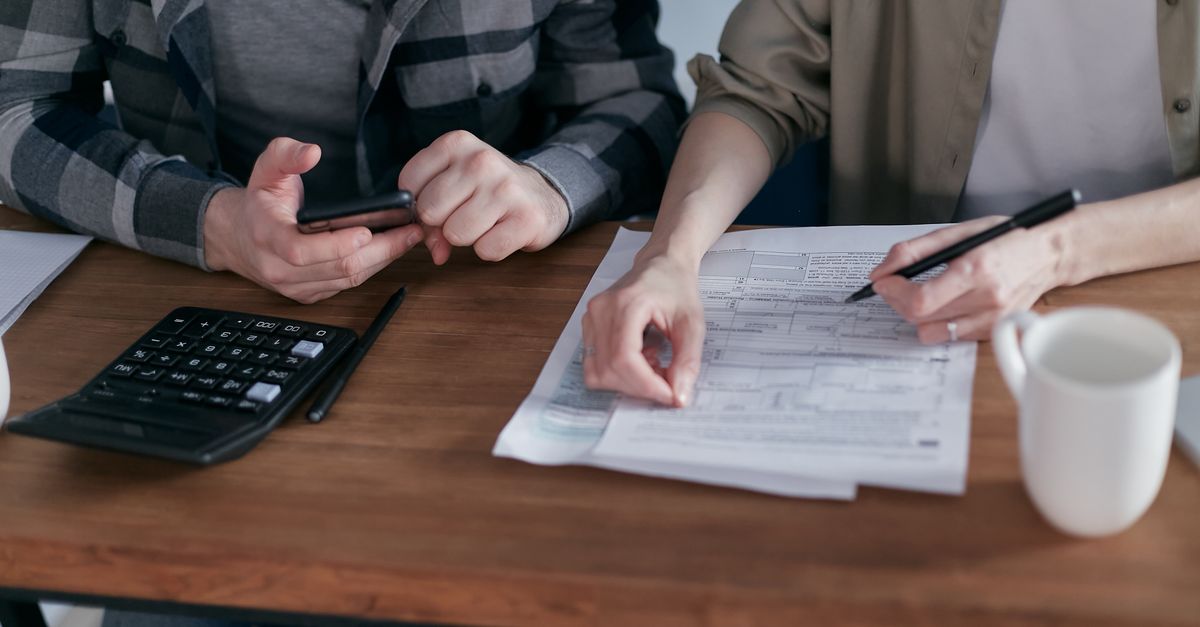 Compare Debt Solutions A couple diligently reviews their finances using a calculator and documents at home.