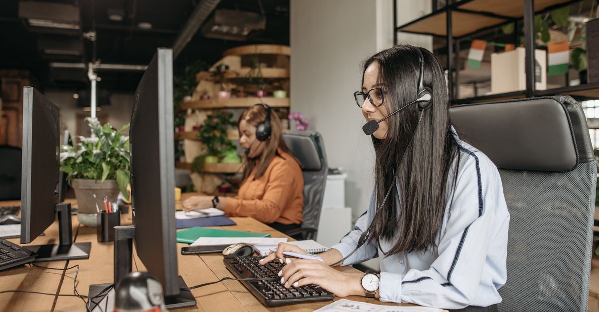 Two women in a modern call center working on computers, providing customer service.