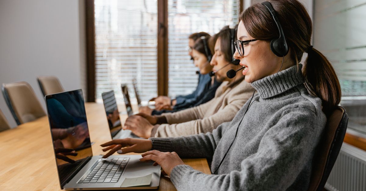 Compare Debt Solutions Professional customer service team working in a modern office setting with headsets and laptops.